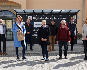 Politische Vertreter und das Team vom Stadtmarketing vor dem digitalen Hauptplatz