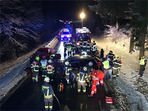 Eine Gruppe von Rettungskräften steht um einen Autounfall herum