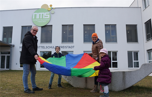 Bürgermeister Christian Gratzl und Stadträtin Karin Kolm stehen mit zwei Kindern vor der Musikmittelschule in Freistadt.